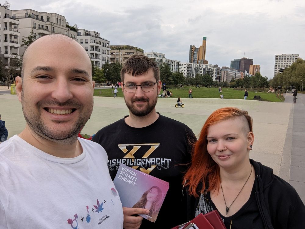 Alex, Henry und ich auf einem Selfie im Park am Gleisdreieck in Berlin mit "Wissen schafft Zukunft"-Flyern und Klemmbrettern