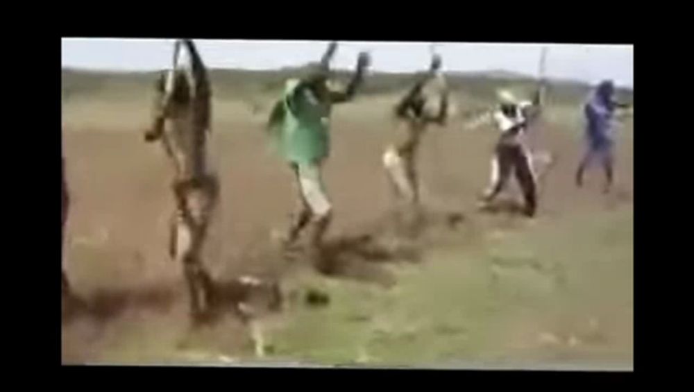 a group of people are jumping in the air in a field while holding sticks .