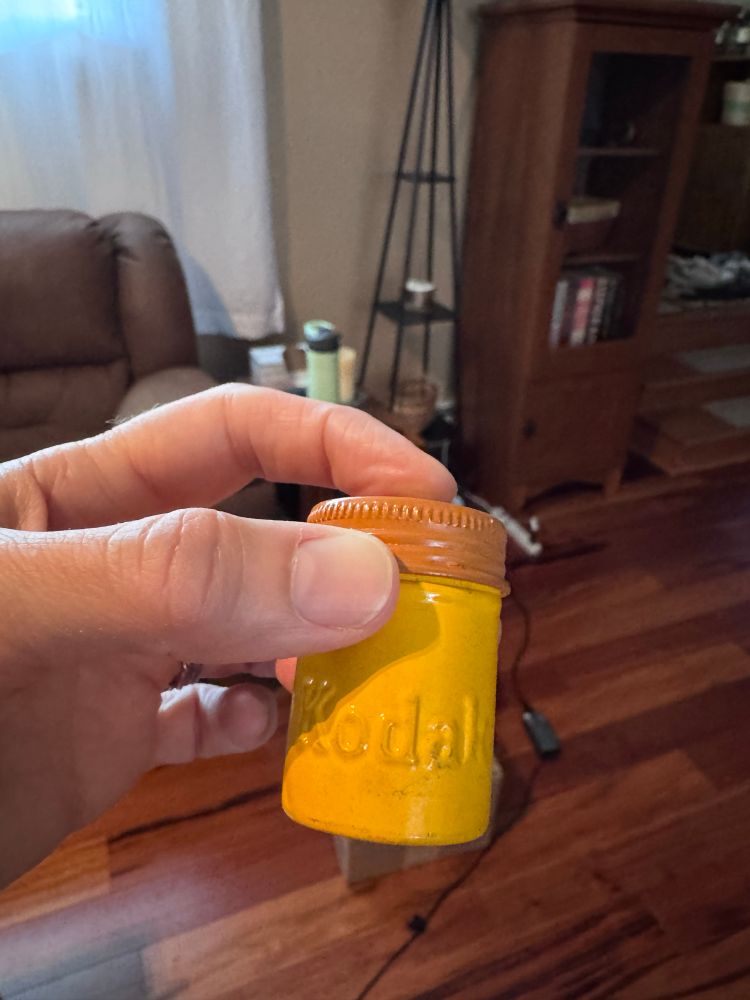 Me holding an old yellow Kodak film canister 