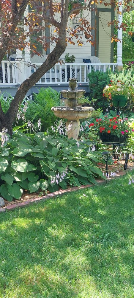 A yard with a small water fountain and house in the background. Wildfire smoke makes the photo appear over exposed