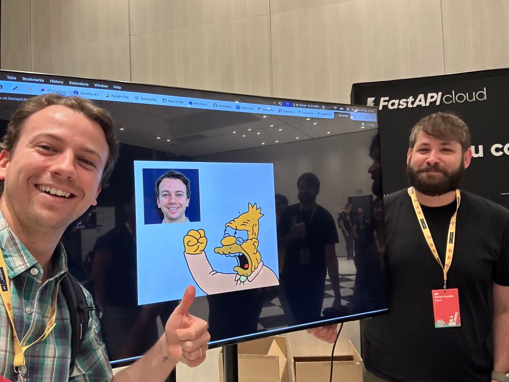 Selfie of me in front of a screen where you can see the grandpa from the Simpsons waving a closed fist at my BlueSky/X profile picture with Patrick on the other side.