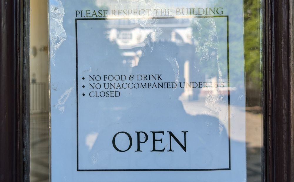 A sign that reads "please respect the building. No food and drink. No unaccompanied under 16s. Closed. OPEN"