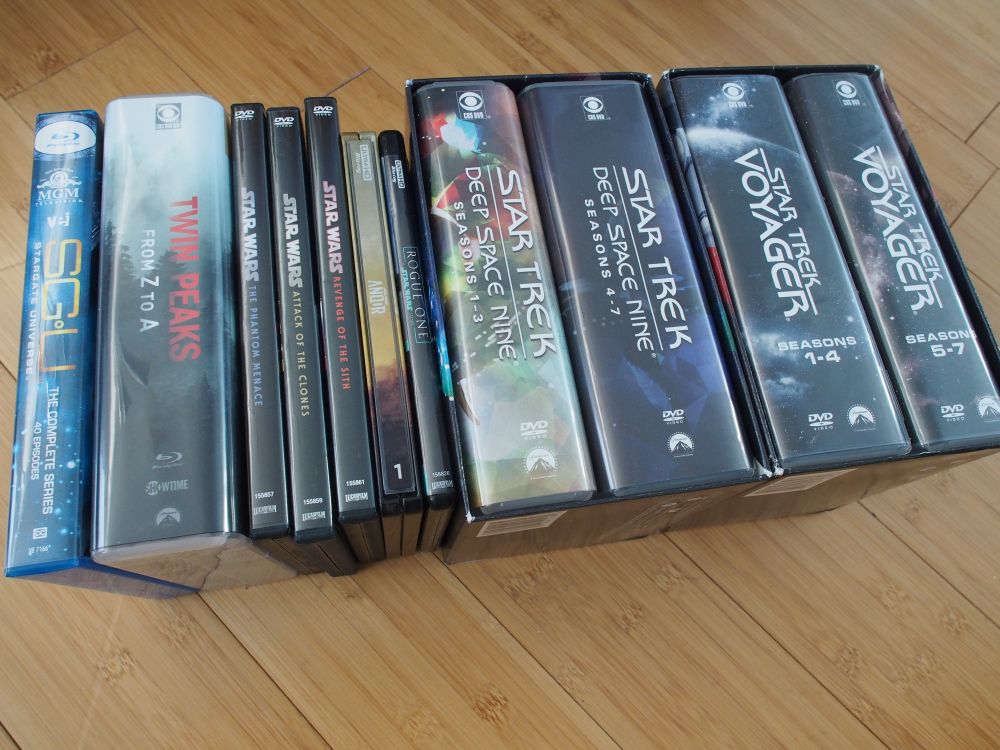 Photo of DVD and Blu-Ray disc sets for, from left to right: Stargate Universe, Twin Peaks Z to A, Star Wars Episode I, Star Wars Episode II, Star Wars Episode III, Andor Season 1, Rogue One: A Star Wars Story, Star Trek Deep Space Nine, and Star Trek Voyager