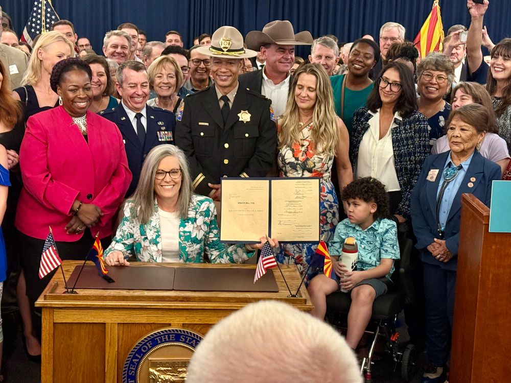 Gov. Katie Hobbs holds up a signed budget bill.