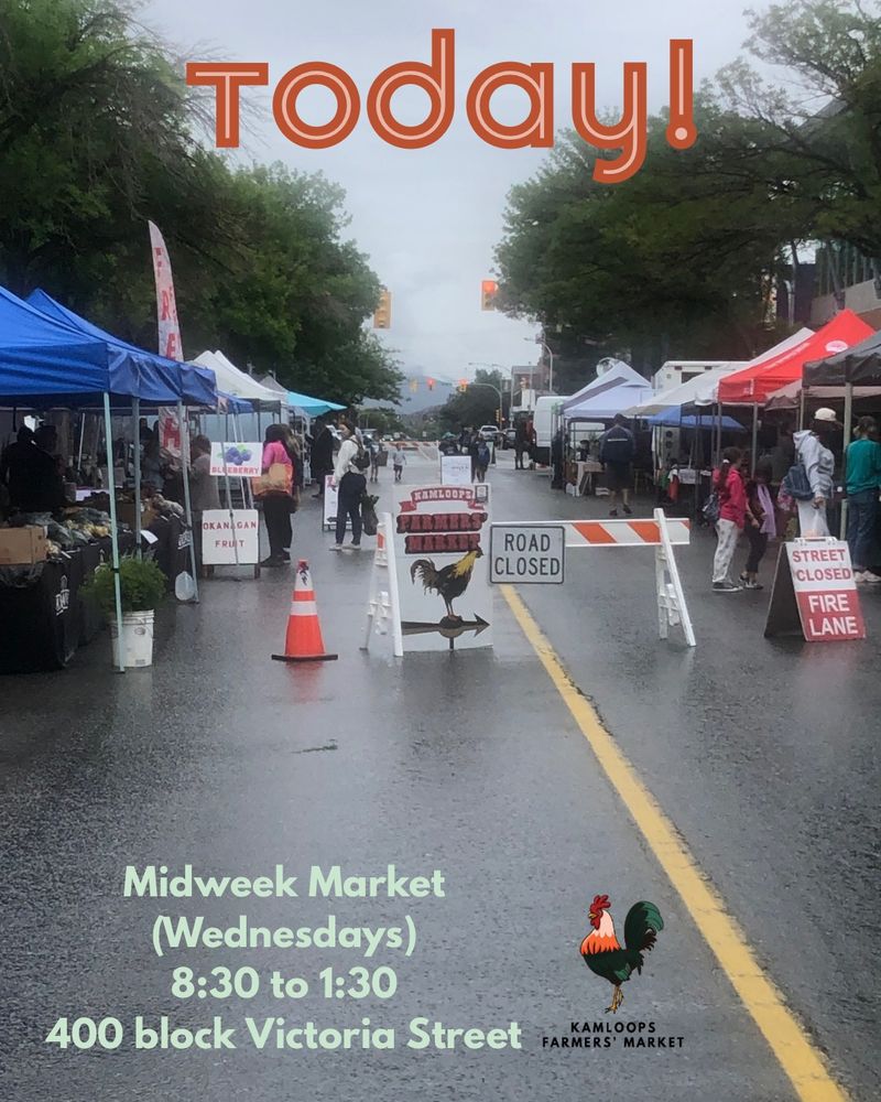 A photo of market on July 9th , 2025—a rainy Midweek Market day.   The photo is from the west entrance near the entrance to the TNRD parkade, and with vendors & market supporters on both sides of the street. In the foreground is an A frame sign that says, “Street closed / Fire Lane” and a barricade which says “Road Closed.” Text on the image says, “Today! Midweek Market (Wednesdays), 8:30 to 1:30, 400 block Victoria Street.” The KFM rooster logo is at the bottom right.