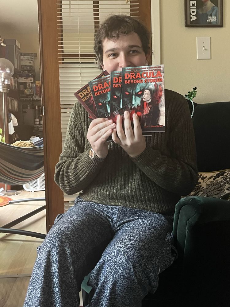 an author holding copies of a fiction collection they contributed to. Clearly delighted.
