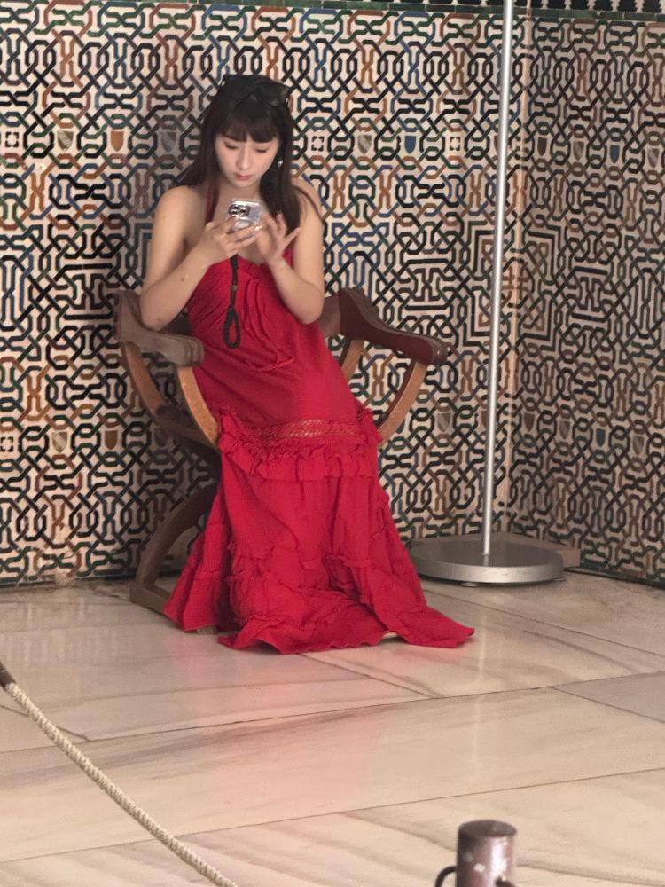 woman in red dress texting in front of ancient Moorish mosaic