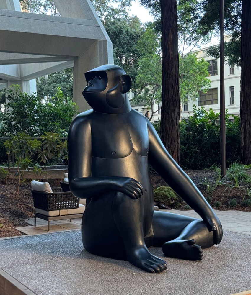 A bronze art-deco sculpture of a gorilla sitting among redwood trees. 