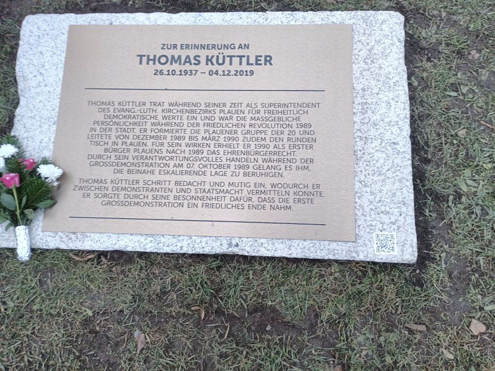 Gedenkplatte im Boden aus Stein mit Inschrift und ein Blumenstrauß 