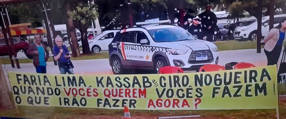 Faixa colocada na frente da PF em Brasília onde o genocida esta preso cumprindo pena por conta de tentativa de golpe: "FARIA LIMA, KASSAB, CIRO NOGUEIRA QUANDO VOCÊS QUEREM VOCÊS FAZEM. O QUÊ IRÃO FAZER AGORA? 
