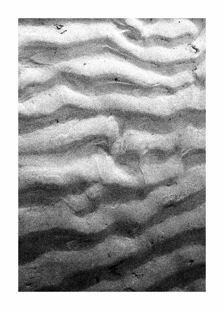 black & white image of ripples in the sand caused by a receding low tide
