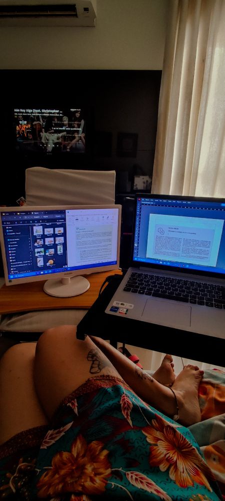 eu sentada muito confortavelmente no sofá na minha casa, com um notebook e um monitor 
no fundo, a tv ligada tocando rbd e a cortina deixando passar uma luz amarela muito confortável 