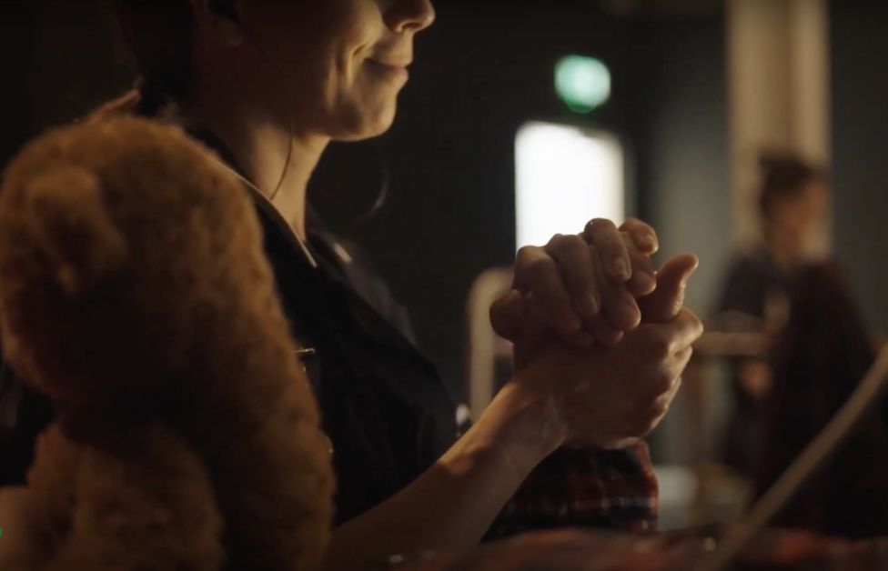 An actress holding the hand of another actor for the ZU-UK performance project Within Touching Distance