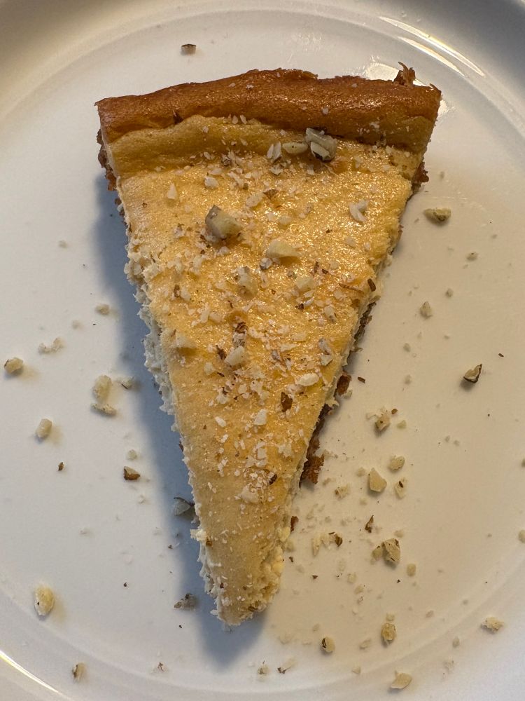 A slice of pawpaw cheesecake with black walnut sprinkled on top.