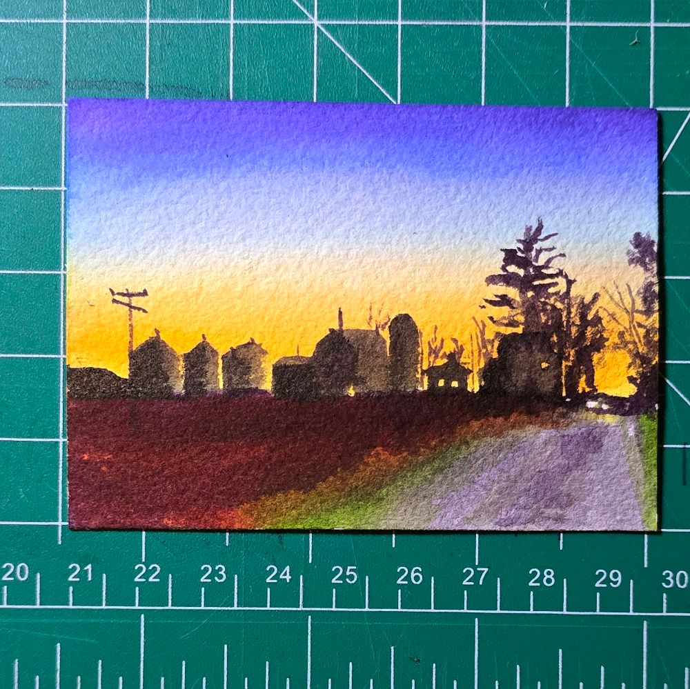 3.5 by 2.5 watercolor painting depicting a colorful sunset behind a large farm on a rural road in Lodi Township, Michigan, near Ann Arbor. A lonely car is cresting the hill with its headlights illuminating the road towards the viewer.