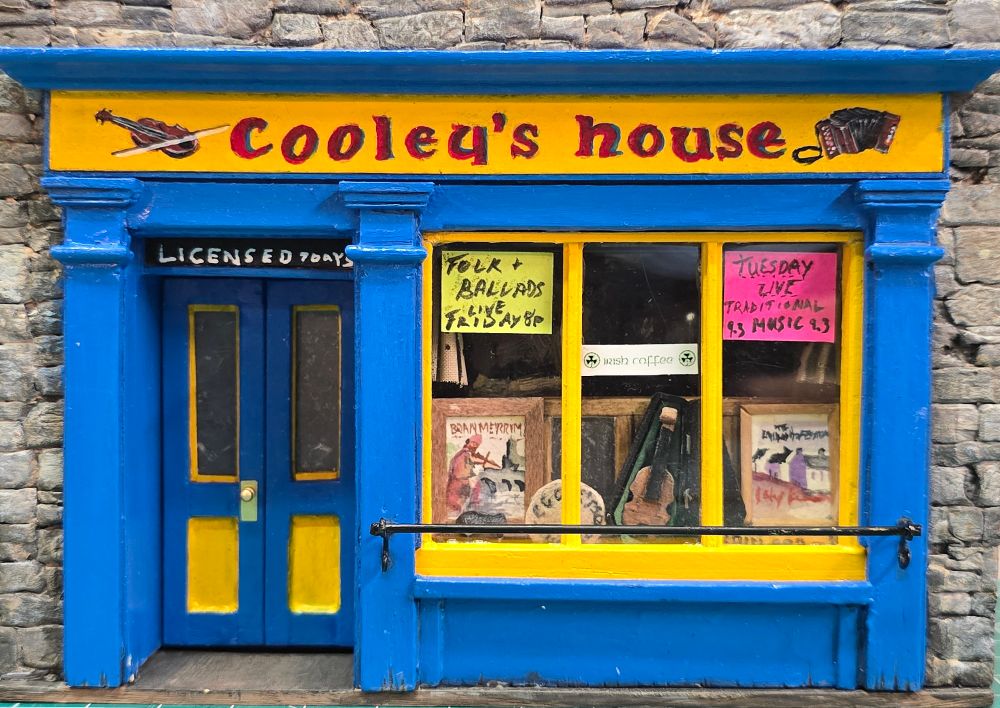 5x7 replica of the front of Cooley's House pub in Ennistimon, County Clare, Ireland.

Stone walls in the backdrop made from XPS foam. Pub facade made of various craft sticks and small moulding with scratch made details in the windows and a hand painted sign.