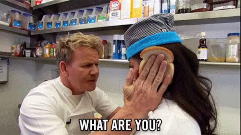 a man is holding a piece of bread over a woman 's face and asking what are you ?