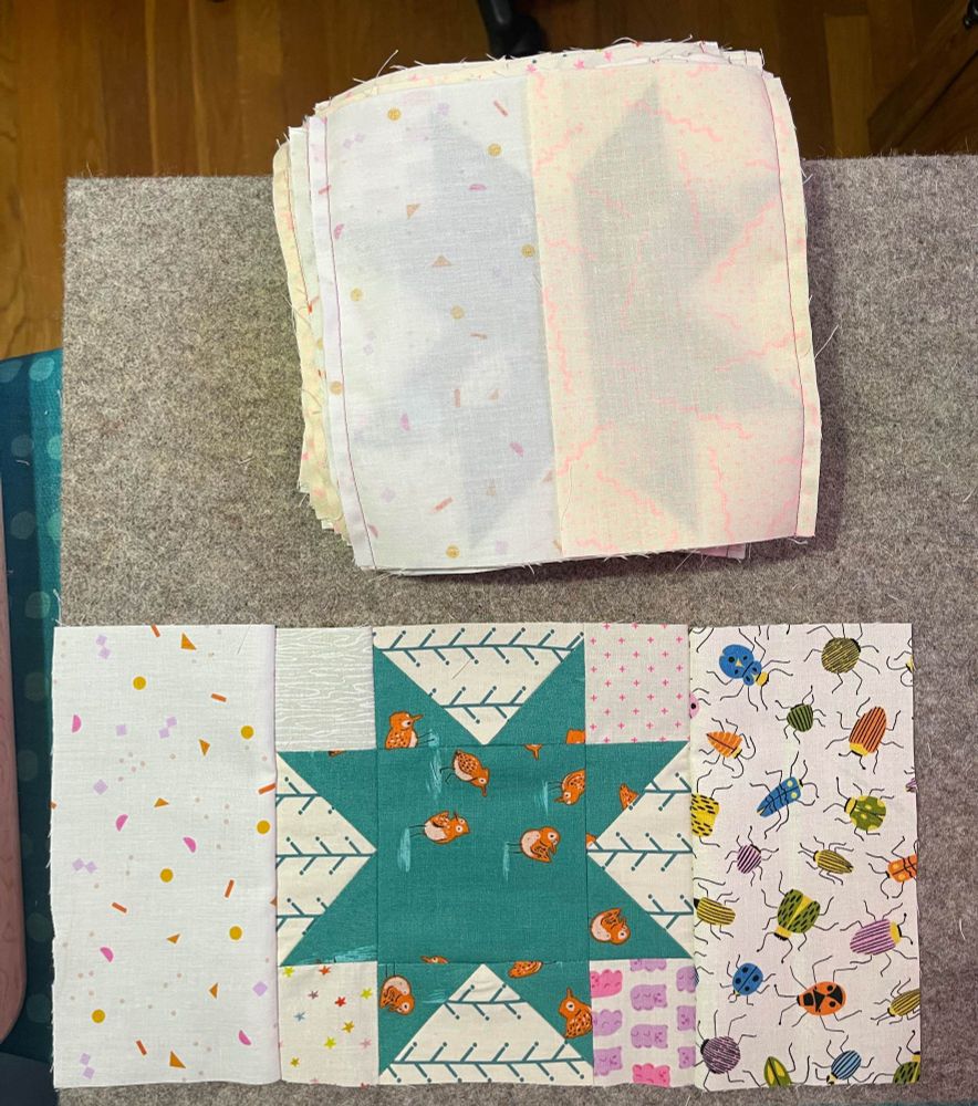 Stack of sewn quilt blocks waiting to be ironed. One block is opened to show what it looks like. Sawtooth star surrounded by low volume fabrics 