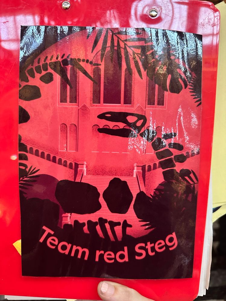 The back of a red clipboard that reads ‘Team Red Steg’, with the cartoon of a fossil Stegosaurus.