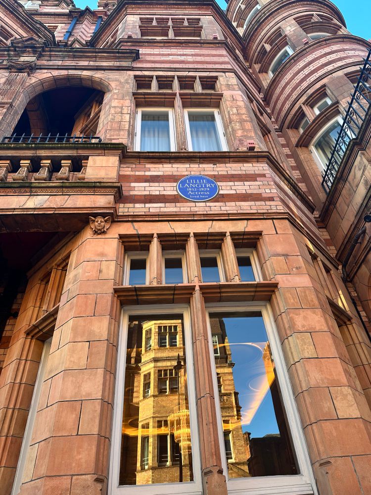 A blue historical plaque high up on a terracotta building. Reads ‘Lillie Langtry 1852-1929 actress love here.’