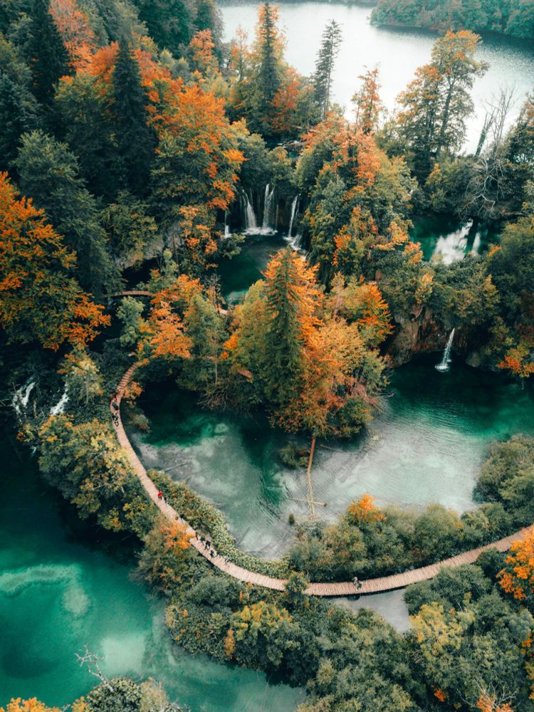 Plitvice Lakes, Croatia with fall trees. The park is famous for its sixteen lakes arranged in cascades, which are separated by natural dams of travertine, a form of limestone. 