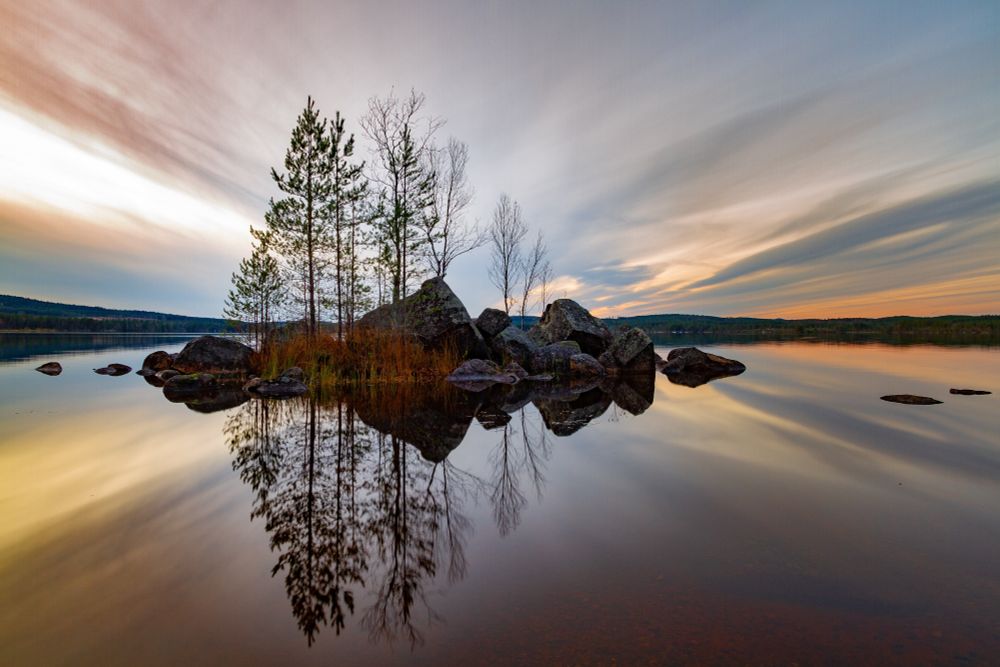 Schweden, Värmland. Värmland is nicknamed “the lake district” thanks to having an impressive 10,000 lakes...very small island of trees in vast lake. soft evening colors