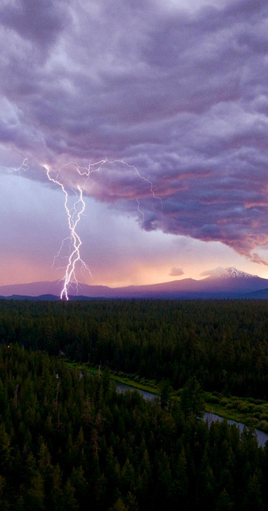 Lightning, storm clouds near the Deschutes River. The background is a chain of volcanoes in the Cascade Mountains.
