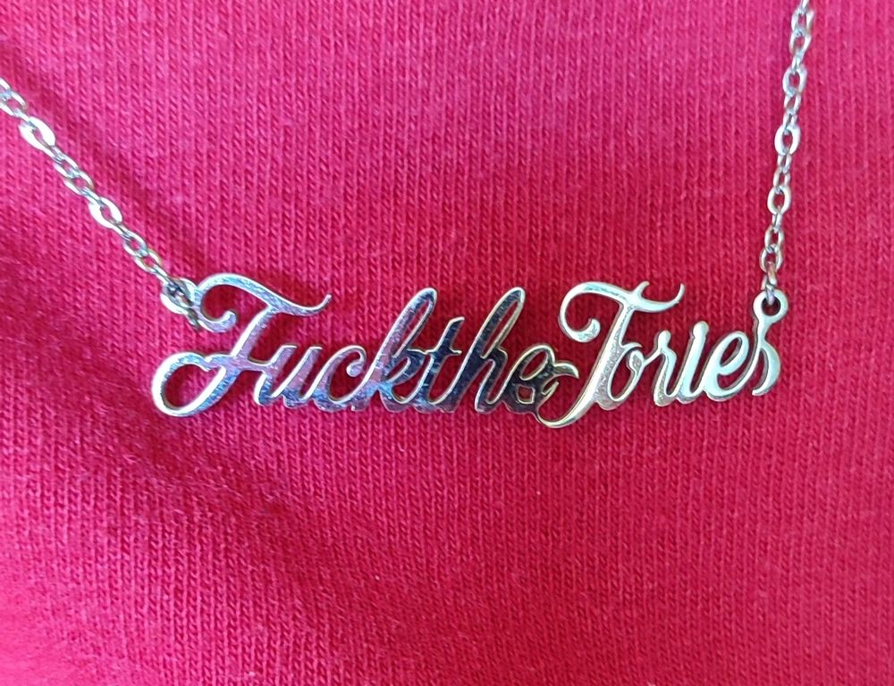 A "Fuck The Tories" necklace with a red t-shirt behind it.