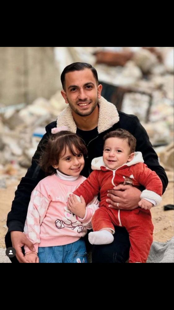 Image of the Gaza journalist Anas Al-Sharif, with his two young children in Jan 2025, posed against a background of ruins and rubble. 