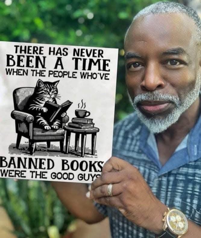 Lavar Burton holds up a book called “There has never been a time when the people who’ve banned books were the good guys.” There is a cat sitting in a chair reading a book with a cup of tea 