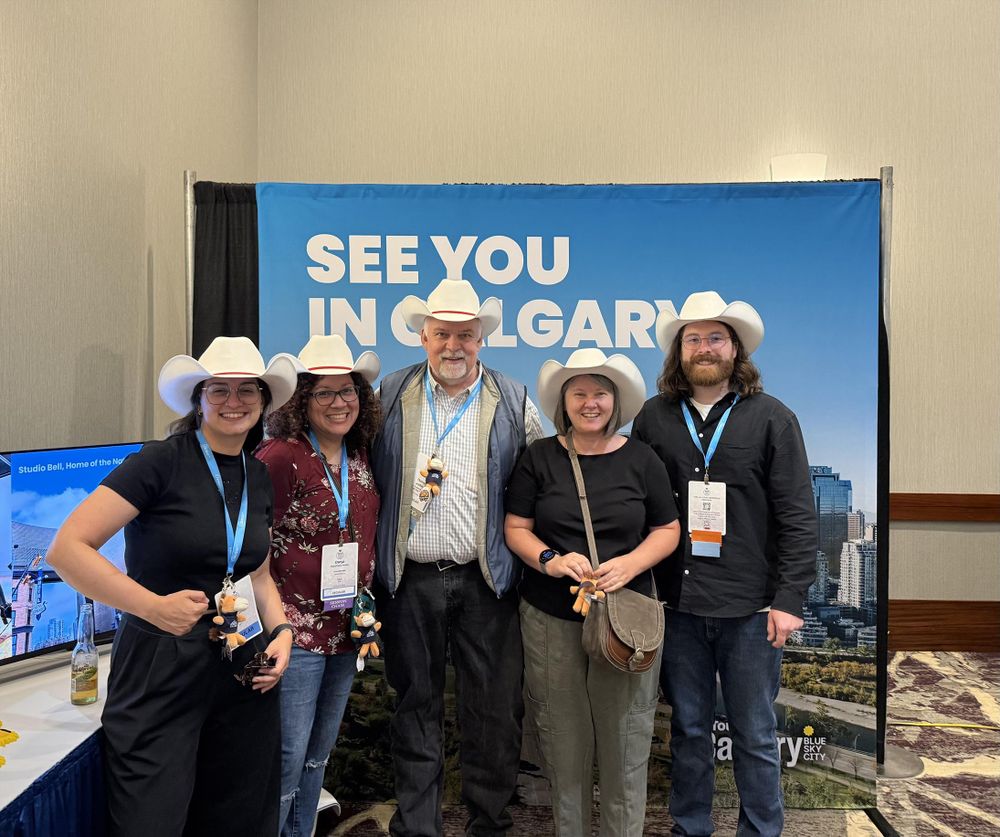 ACA2025 attendees wearing cowboy hats in front of a billboard that says "See you in Calgary!"