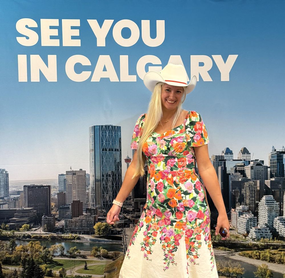 ACA2025 attendee wearing cowboy hat in front of a billboard that says "See you in Calgary!"