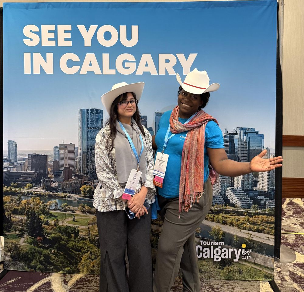 ACA2025 attendees wearing cowboy hats in front of a billboard that says "See you in Calgary!"