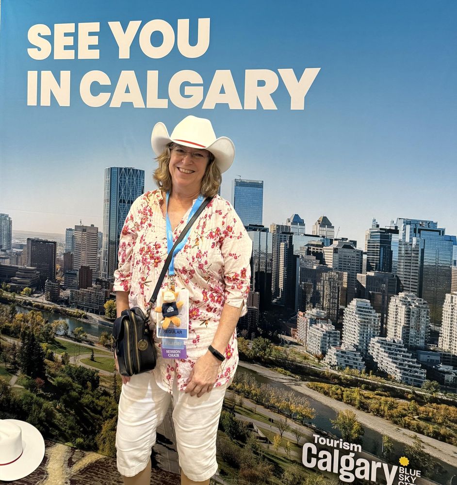 ACA2025 attendee wearing cowboy hat in front of a billboard that says "See you in Calgary!"