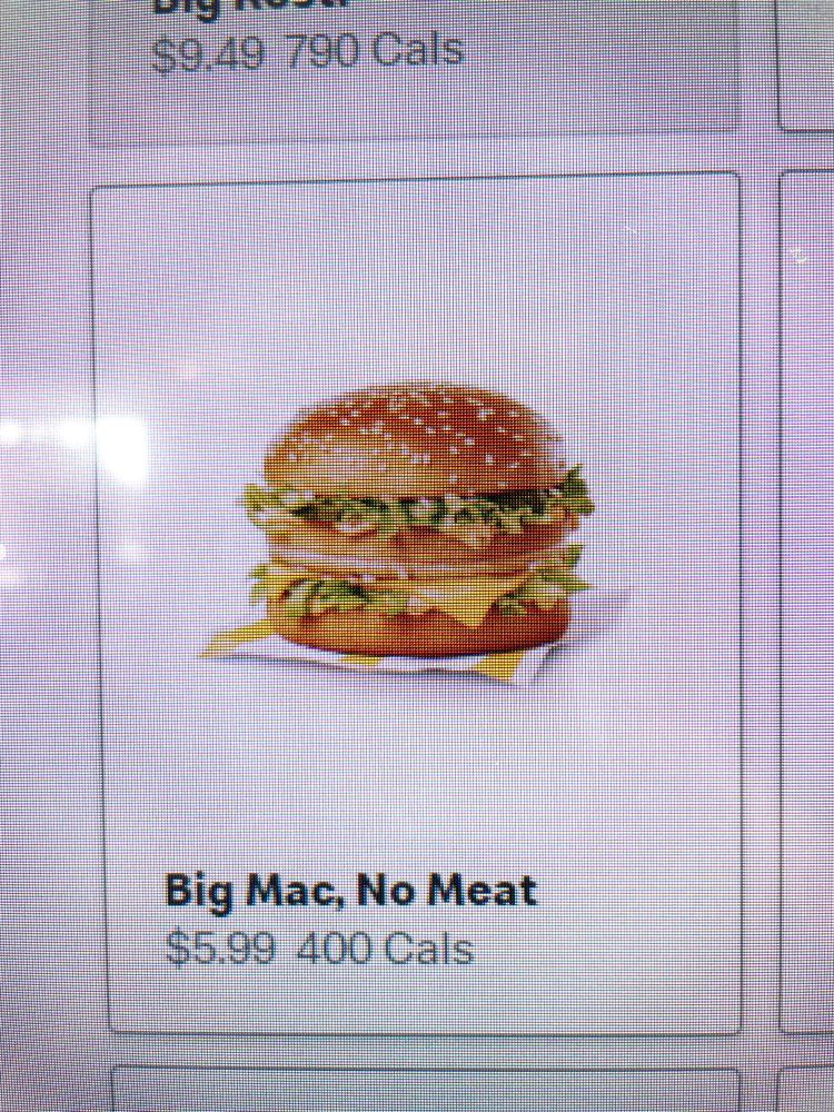 Photo taken of a McDonalds touch screen menu item. It shows a Big Mac sandwich with no meat patties, screen reads: “Big Mac, No Meat” “$5.99” “400 Cals”.