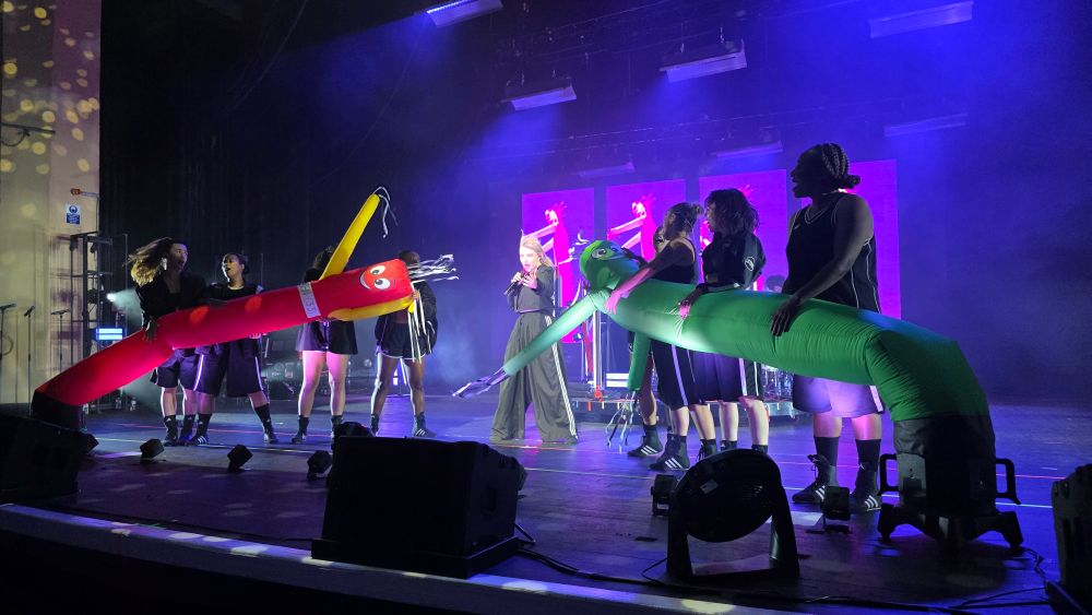 Self Esteem performing in between two giant inflatable wavy guys more usually seen waving around outside retailers