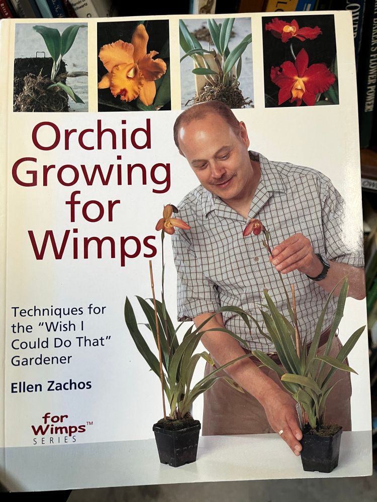 The cover of the book “Orchid Growing for Wimps” featuring a balding man with a thin mustache and plaid shirt posing with two potted lady’s slipper orchids.