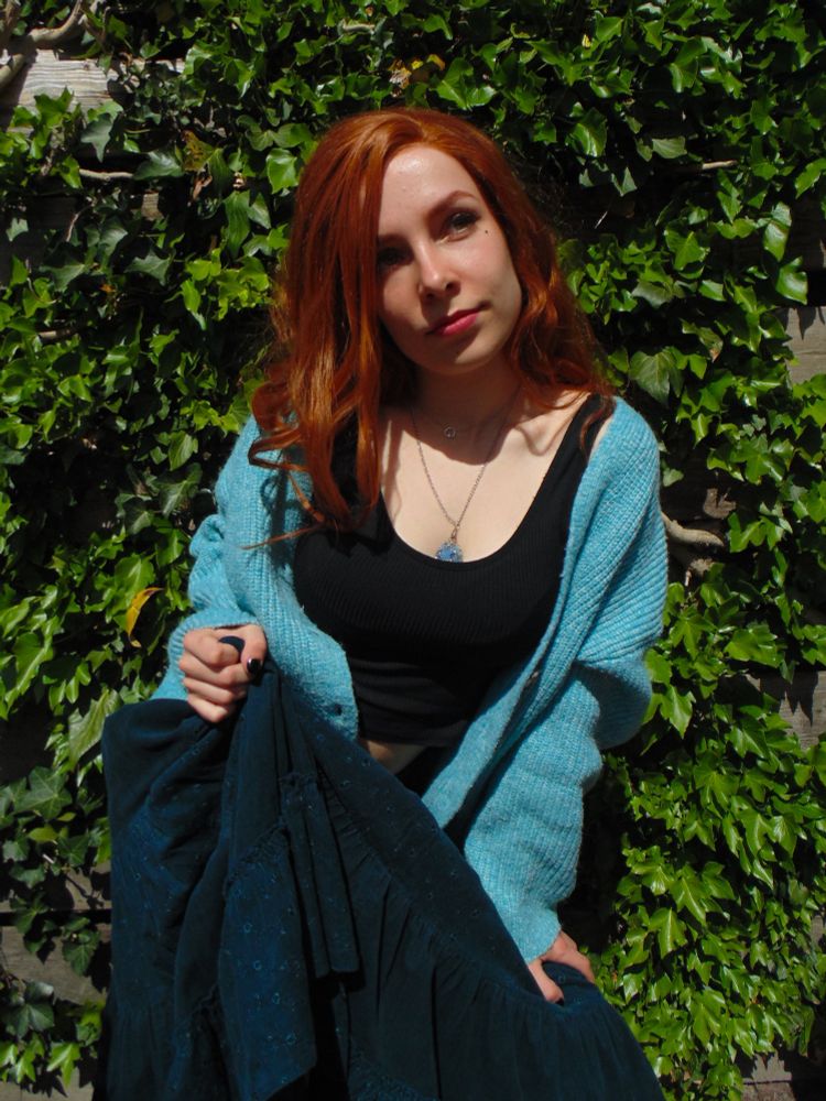 Same cosplay. Now holding skirt up in one hand and looking off camera to the right