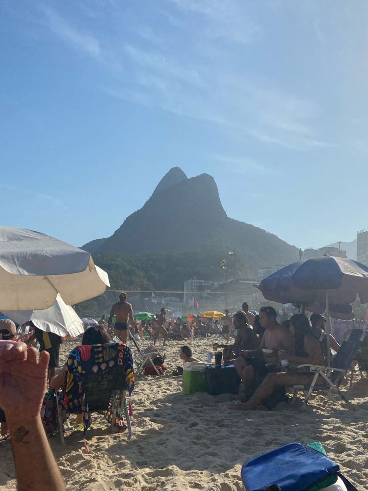 Praia do Leblon em um dia ensolarado com o Morro Dois Irmãos ao fundo.