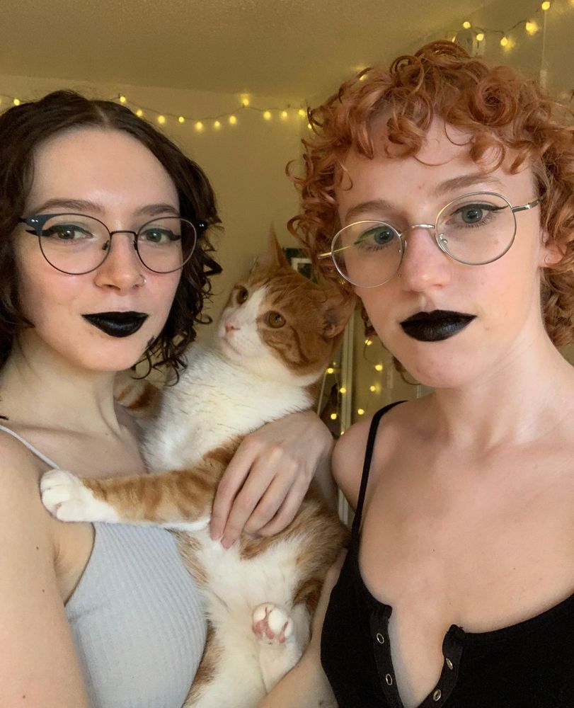 Serana (left) and Bee (right) posing with their cat Chu Chu (center)