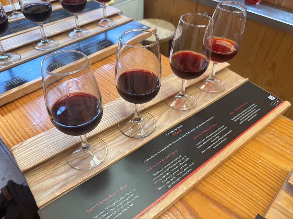 A row of four glasses of port on a wooden board