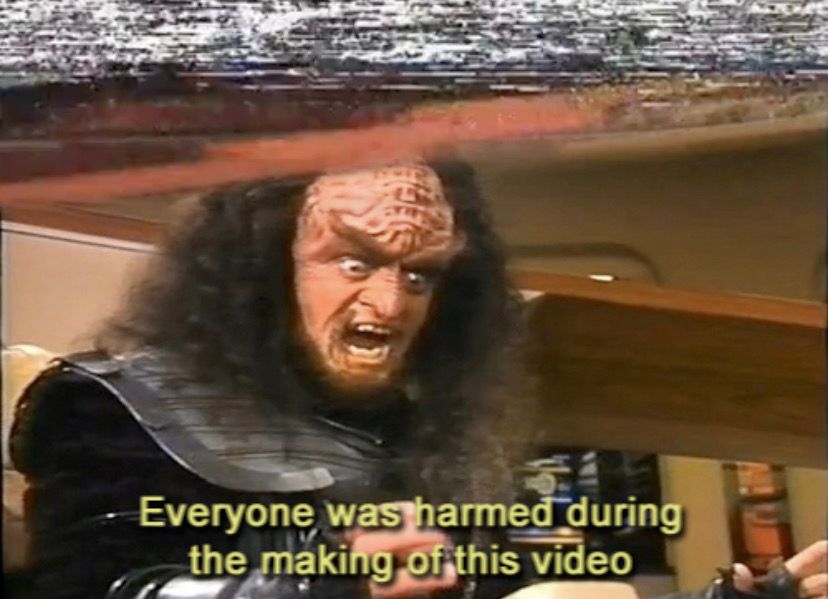 A Klingon officer with frizzy dark brown hair, prominent eyebrows, and a manic expression shouts, ‘Everyone was harmed during the making of this video’