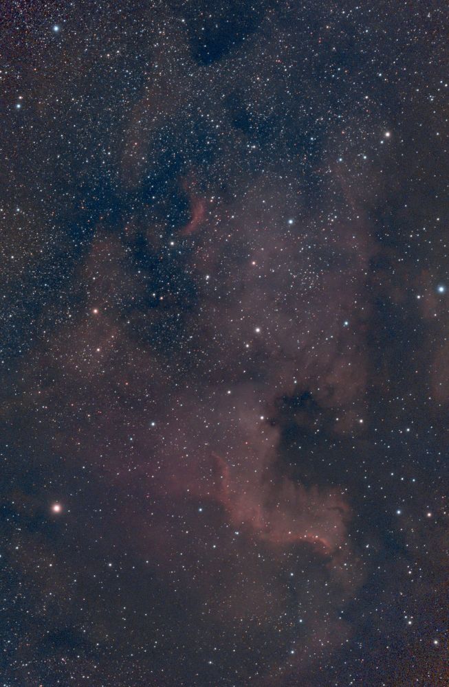 A reddish emission nebula that is roughly shaped like the North American continent. Bottom-ish right, a darker area marks the continent's Gulf of Mexico.