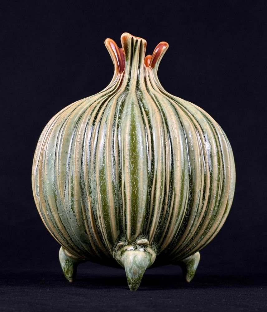handmade carved bud vase with tripod feet, glazed in green and magenta