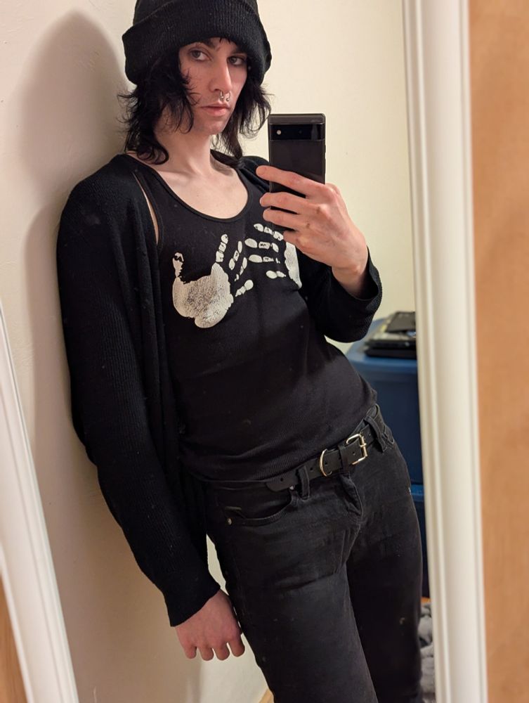 Mirror shot of Hex in all black; jeans, tank, cardigan, and beanie