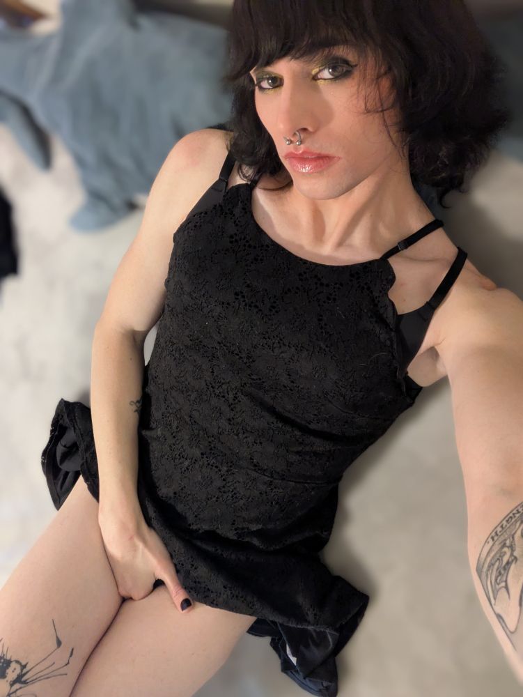 Hex, laying on her bed, wearing a black dress, with her hand between her legs.