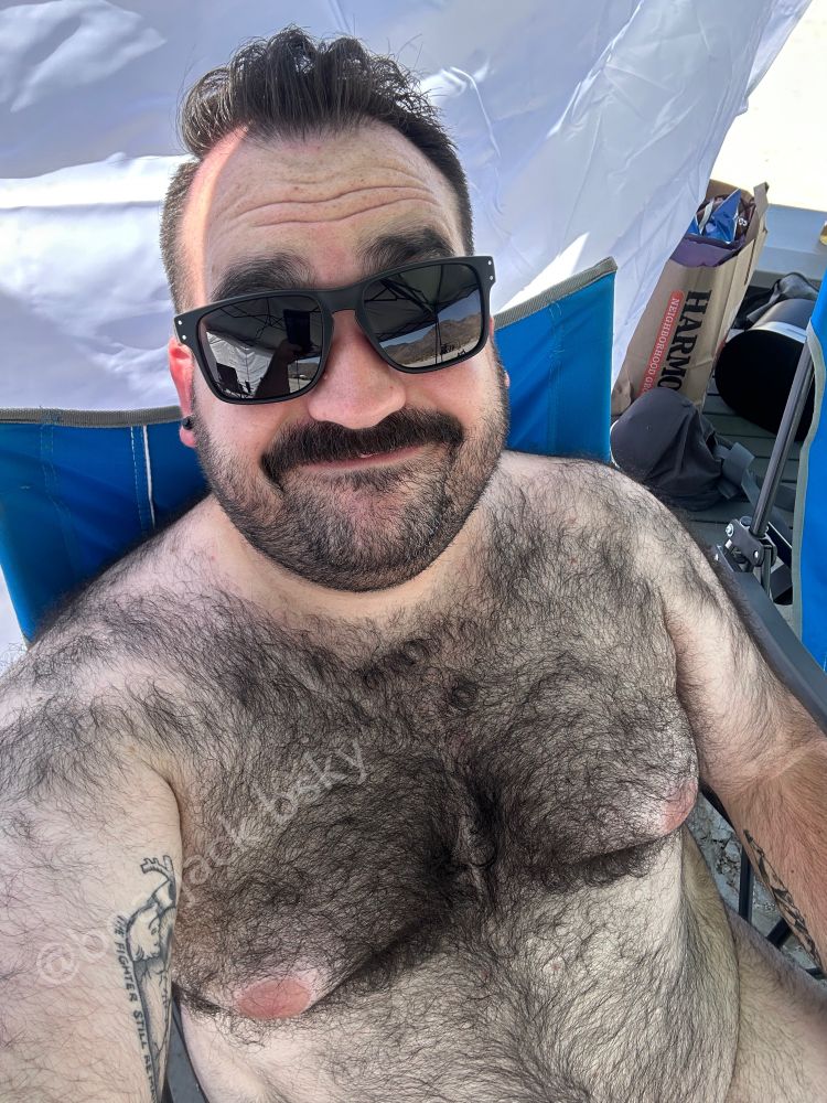 A hairy shirtless man sitting in a chair