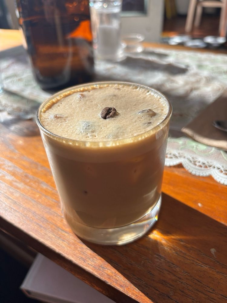 A glass of Thai iced coffee decorated with a coffee bean. 