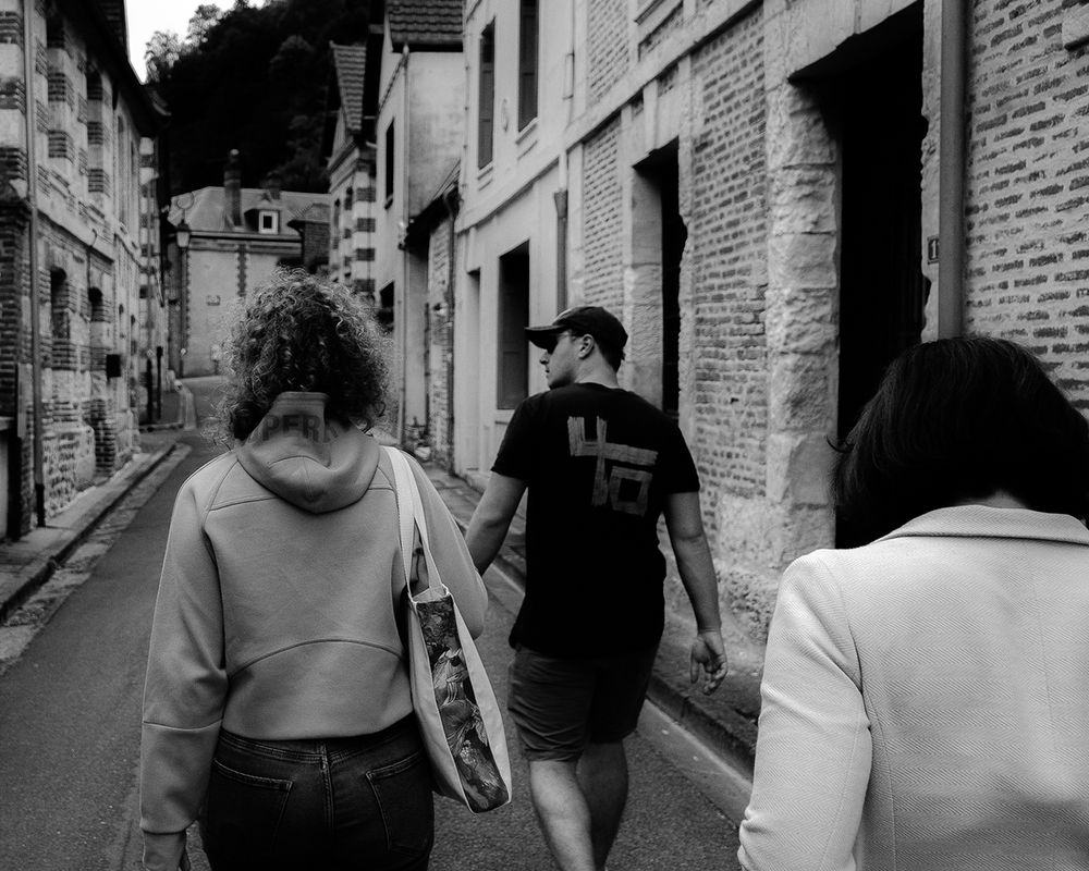 Three people with their backs to a street in the town of La Bouille in Normandy.