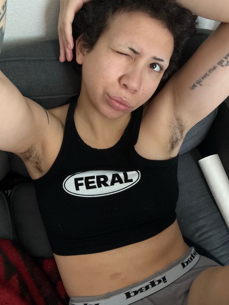 angel winking at the camera in a black tank top thats says feral and grey boxers
